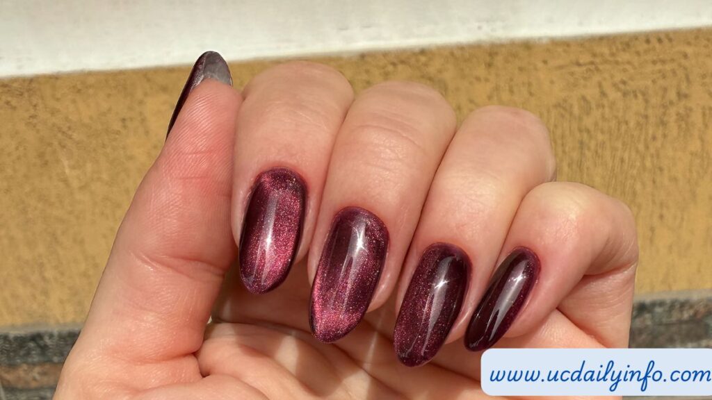 Short rounded cherry red nails beside a white cotton sleeve